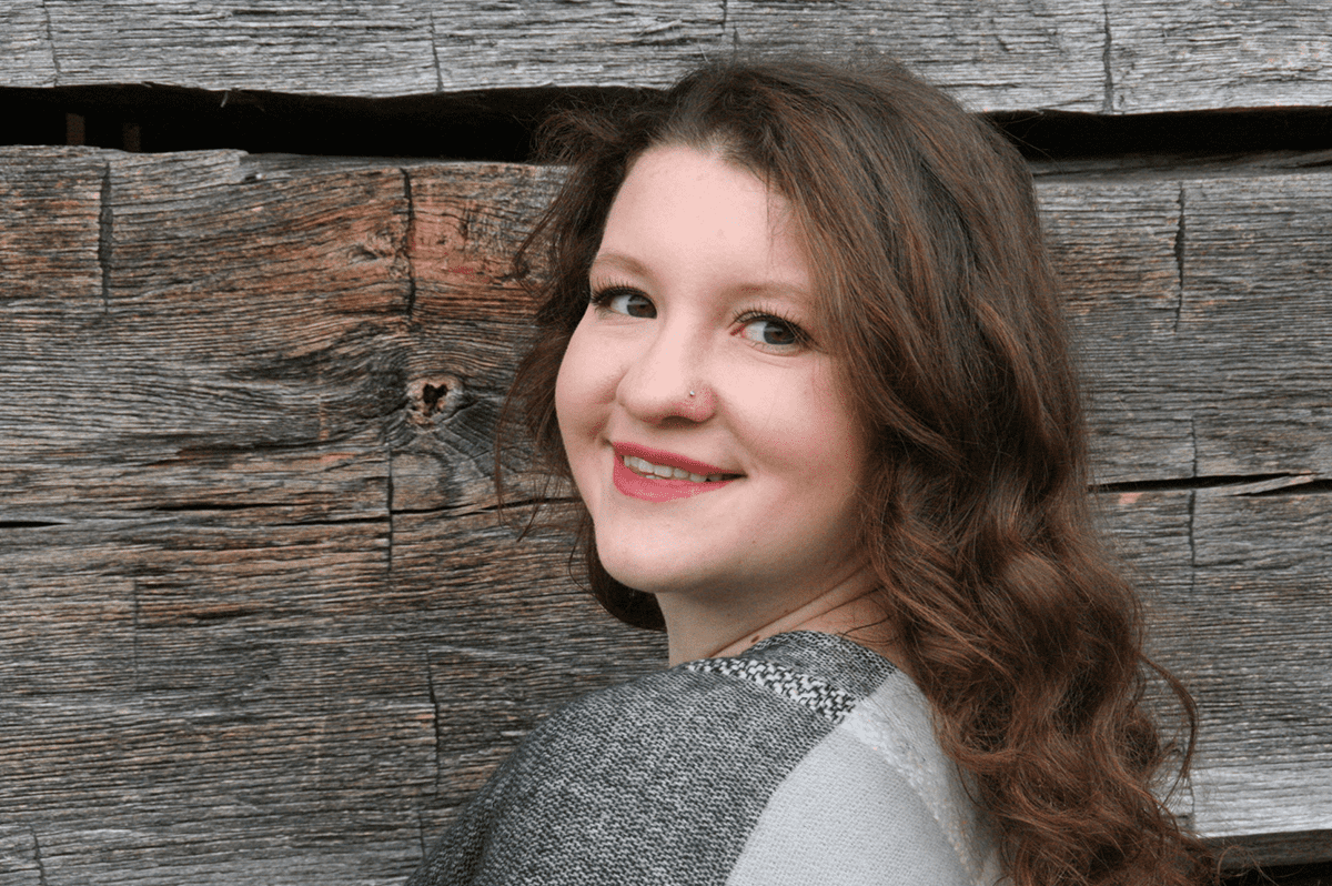 W&J Senior Cayleigh Pratt smiles against a wooden backdrop.