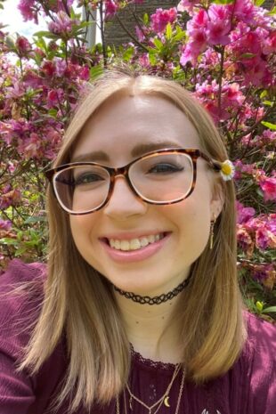 W&J senior Isabell Kratz smiles in front of pick flowers.