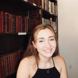 W&J senior Lily Bonasso sits in front of a bookcase and smiles.