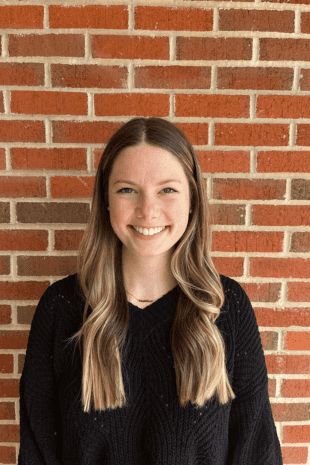 W&J senior Madeline Hubbard smiles in front of a brick wall.