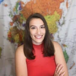 W&J senior Maria Sherwood poses with arms crossed in front of a map.